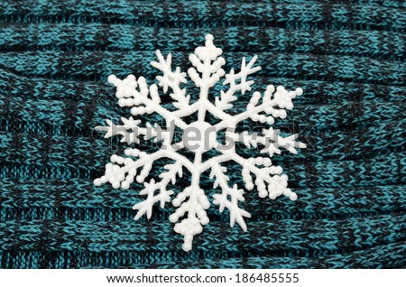 Big white snowflake on gray and blue knitted wool background. 
