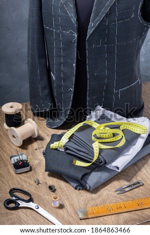 suit jacket on male tailor mannequin and sewing tools, creative concept of clothes atelier