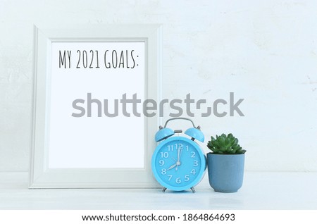 Business concept of top view 2021 goals list over frame, home plant over wooden desk