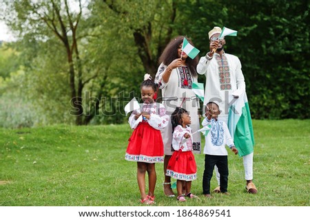 African family in traditional clothes with nigerian flags at park. 