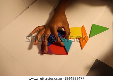 Close up on hands of small Child solving Tangram puzzle white background