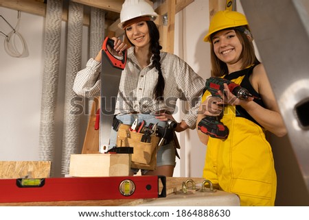 A brunette with a braid and a blonde with short hair are waiting for the start of a new job on the construction site.