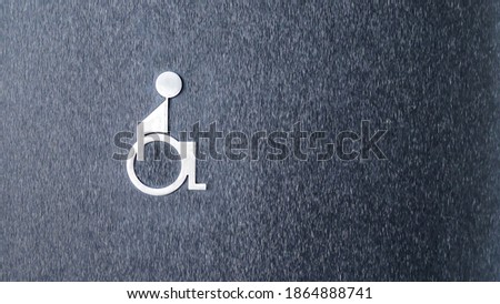 The symbol of the disabled toilet on the black wall
