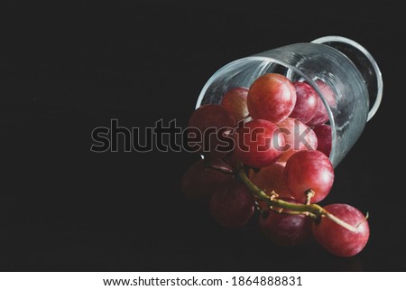 Red grapes, large bunch of fruits, fresh and tasty simple food on a dark background in a fancy minimal composition