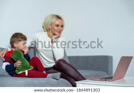 Mom and son will watch cartoons together at home at the computer. Mom and son are watching cartoons on a laptop.