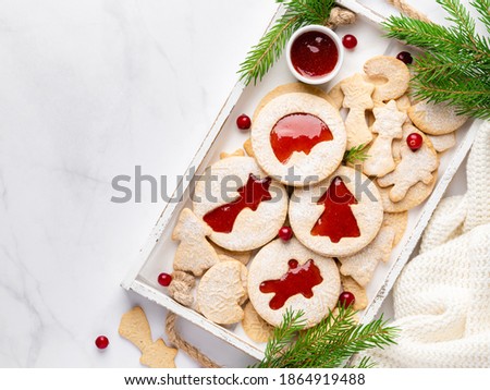 Linzer and gingerbread cookies in wooden tray. Christmas and winter flatlay. Layout template, copy space, place for text. New year and christmas white background. Fir branches, cranberry, pullover.