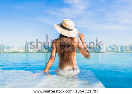 Portrait beautiful young asian woman smile relax leisure around outdoor swimming pool with city view