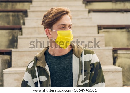 Athletic young and handsome man in sportswear wearing a yellow mask. Attractive male model wearing a yellow medical mask due to Covid-19 measures. Caucasian man wearing a mask to protect himself 