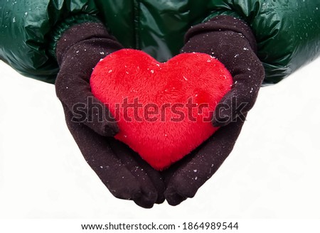 Red, fluffy, plush heart. A girl in winter clothes holds a heart in her hands close-up on a white background. Valentine's day concept