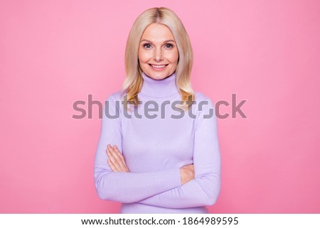 Photo portrait of smiling elder woman wearing purple turtleneck folded hands isolated on pastel pink color background