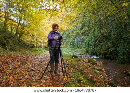 Woman nature photographer with professional camera hiking by the river