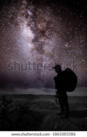 Silhouette of man with backpack and trekking poles against amazing Milky Way at night. Photographer and star in the night sky.