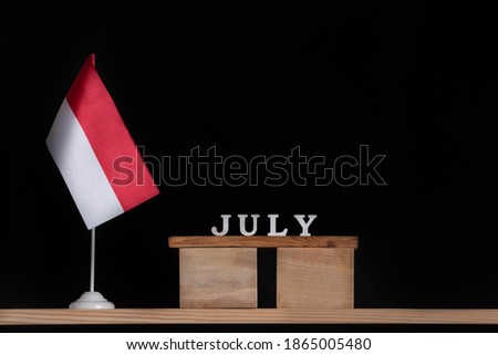 Wooden calendar of July with Polish flag on black background. Holidays of Poland in July