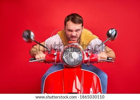 overjoyed mad crazy man driving moped fast speed wearing casual clothes isolated over red background