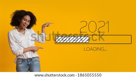 Waiting For 2021 New Year. Joyful Black Woman Pointing Finger At 2021 Loading Process Bar Standing Over Yellow Background. Anticipation, Awaiting Upcoming Better Year Concept. Panorama Royalty-Free Stock Photo #1865055550