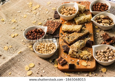Granola Bars and mixed nuts. Honey bars with peanuts, chocolate, dried fruit, sesame and sunflower seeds