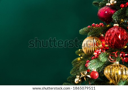 Decorated with ornaments and lights Christmas tree on dark green background. Merry Christmas and Happy Holidays greeting card, frame, banner. New Year. Noel. Winter holiday theme. 

