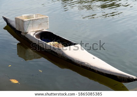 Old plastic boat on the river with foam box on top.