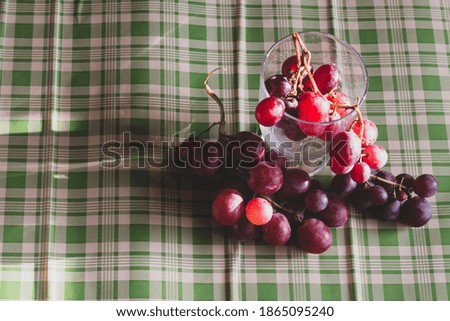 Red grapes, large bunch of fruits, fresh and tasty simple food with brights red and violet colors on a green background in an amazing composition