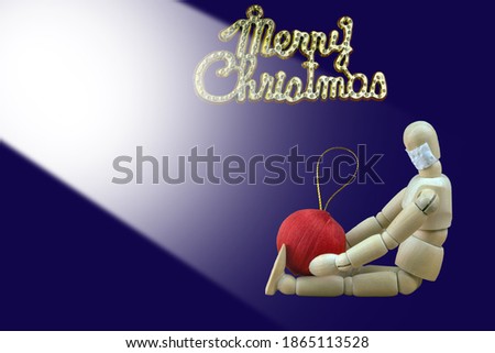 A wooden  mannequin imitate the action of people. The objects are isolated on a dark blue background. Lonely Christmas during the COVID-19 pandemic.