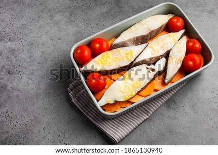 Chilled halibut steaks in a baking dish with tomatoes and sweet potatoes. Copy space. Fish dish.