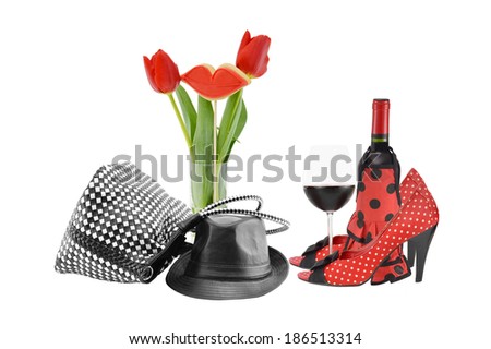 Leather Hat and Handbag Floral Arrangement High Heel Pumps Red Wine Bottle Stemware isolated on white background