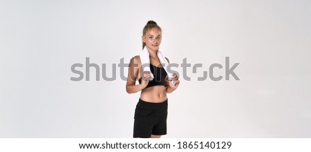 Portrait of cute sportive girl child in black sportswear looking at camera, holding towel around her neck while standing isolated over white background. Sport, training, fitness concept. Web Banner