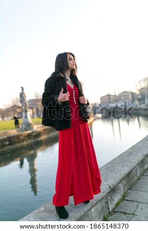 beautiful girl with long black hair standing at the edge of the canal in the square in padua. High quality photo