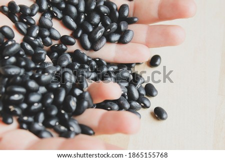 Black beans trickle from your hands onto the kitchen counter.
