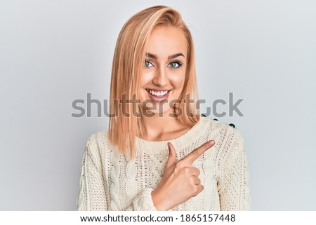 Beautiful caucasian woman wearing casual winter sweater smiling cheerful pointing with hand and finger up to the side 