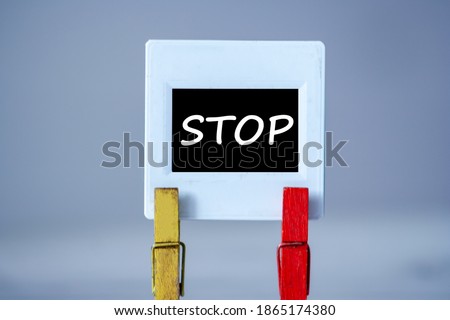 Plastic frame with clothes pin on table. White frame with black background and inscription word STOP. STOP concept.