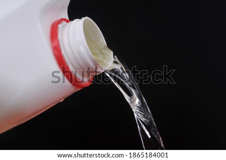 Pouring bleach close up on black background Royalty-Free Stock Photo #1865184001
