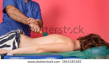 male masseur doing medical back massage with roller