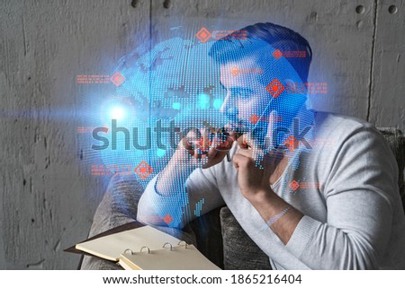 Handsome businessman in casual wears, speaking phone, taking notes at office try to solve global international issue. Double exposure. The concept of international business. Planet hologram.