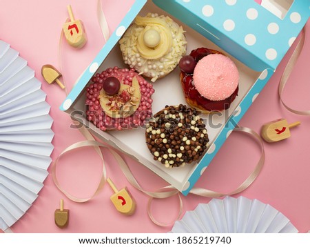 Top view image of jewish holiday Hanukkah background with traditional donuts in the box and wooden dreidel (spinning top).
