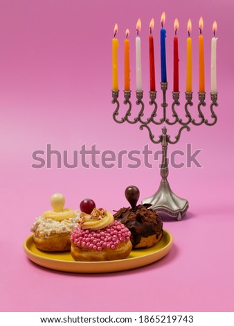 Image of jewish holiday Hanukkah background with traditional donuts menorah (traditional candelabra) and burning candles. 