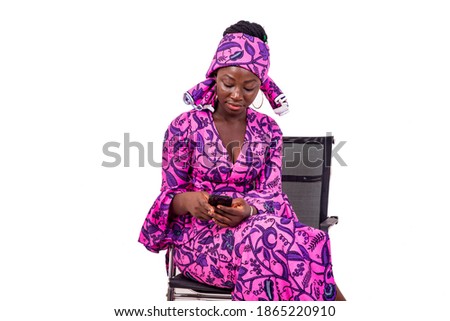 portrait of a beautiful happy young businesswoman wearing traditional loincloth sitting on a chair using a mobile phone.