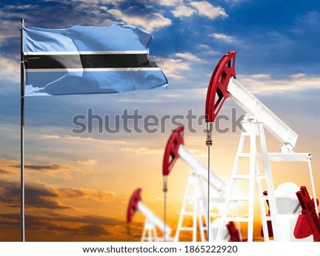 Oil rigs against the backdrop of the colorful sky and a flagpole with the flag of Botswana. The concept of oil production, minerals, development of new deposits.