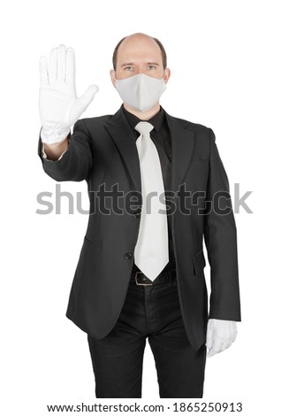 Handsome young business man holding surgical medical virus protection mask with white gloves showing stop gesture isolated on white
