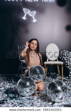 Attractive young girl with vening make-up in an evening dress in a floor dress near a fireplace in a bright studio. New Year 2021. Happy New Year. Christmas photo