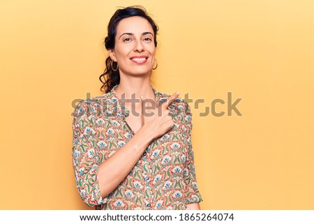 Young beautiful hispanic woman wearing casual clothes smiling cheerful pointing with hand and finger up to the side 