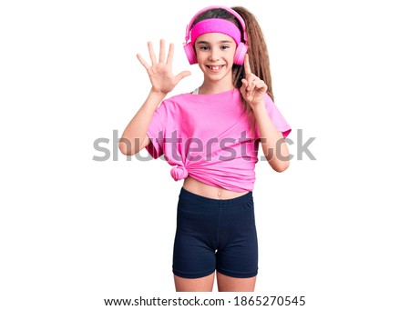Cute hispanic child girl wearing gym clothes and using headphones showing and pointing up with fingers number six while smiling confident and happy. 