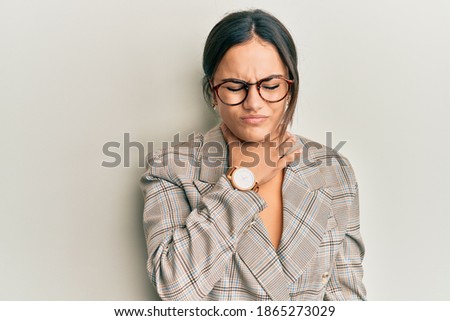 Young brunette woman wearing business jacket and glasses touching painful neck, sore throat for flu, clod and infection 