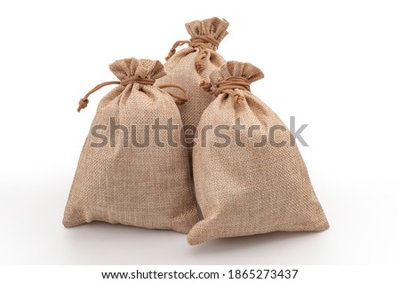 Agricultural hessian cloth sacks, rough sack material and linen fabric textile concept with pile of three brown burlap or sackcloth bags isolated on white background with clipping path cutout Royalty-Free Stock Photo #1865273437