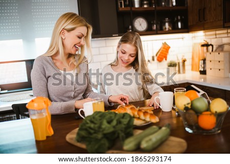 Happy mother and daughter making breakfast at home kitchen and spend time together