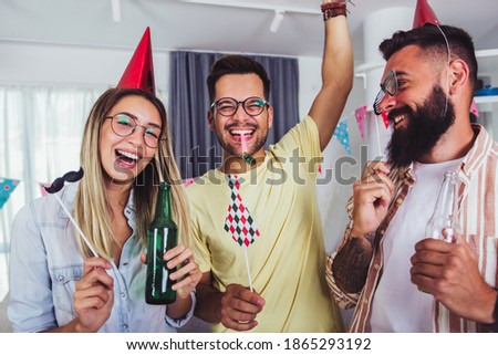 Group of happy people celebrating birthday among friends and smiling while having a party