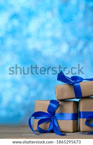 Christmas or birthday presents. Craft paper wrapped gift boxes on blue bokeh background. Vertical shot