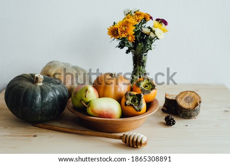 Happy Thanksgiving. A plate of natural material. Reusable utensils. Eco-friendly tableware. Pumpkins, pears and persimmons. Festive composition with an autumn bouquet of flowers, fruits, vegetables.