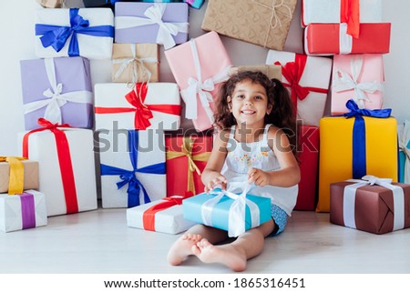 Little curly girl opens festive birthday gifts