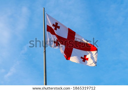 Georgian flag waving in the wind on the background of blue, clear sky